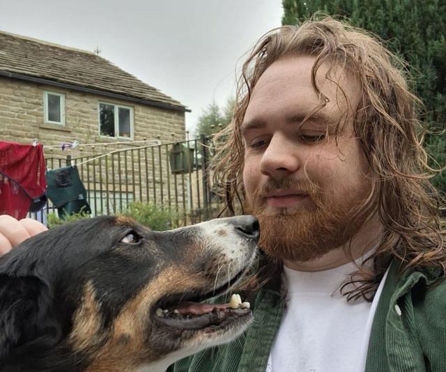 Canine coach Max face to face with a happy black, white and tan dog outdoors